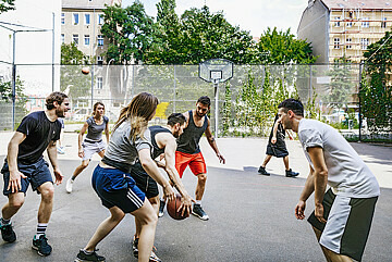 Eine Gruppe junger Leute spielt Basketball.